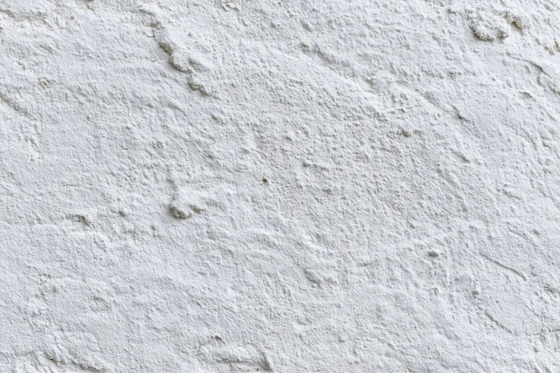White painted concrete wall surface filling the frame with rough texture and even lighting