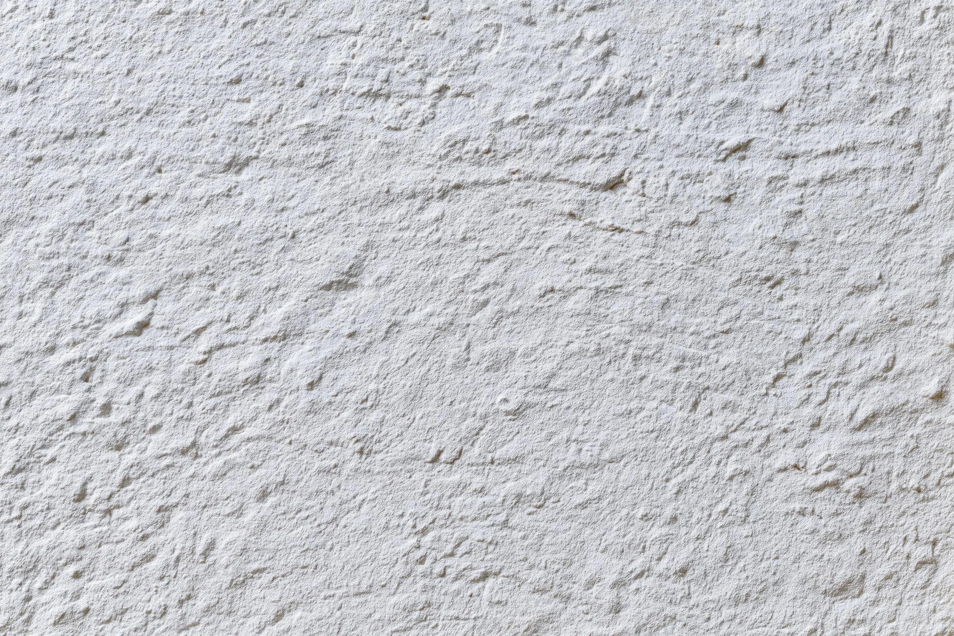 White painted concrete wall surface filling the frame with rough texture and even lighting