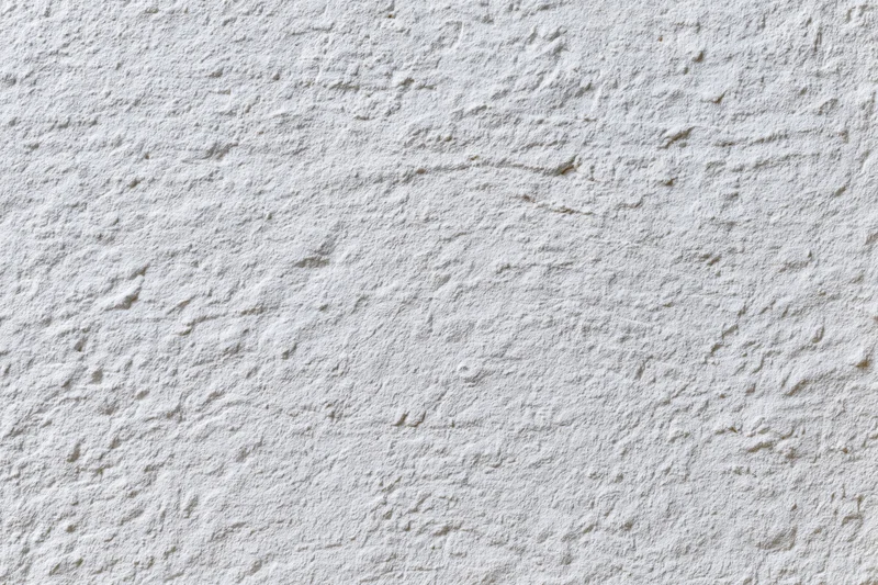 White painted concrete wall surface filling the frame with rough texture and even lighting