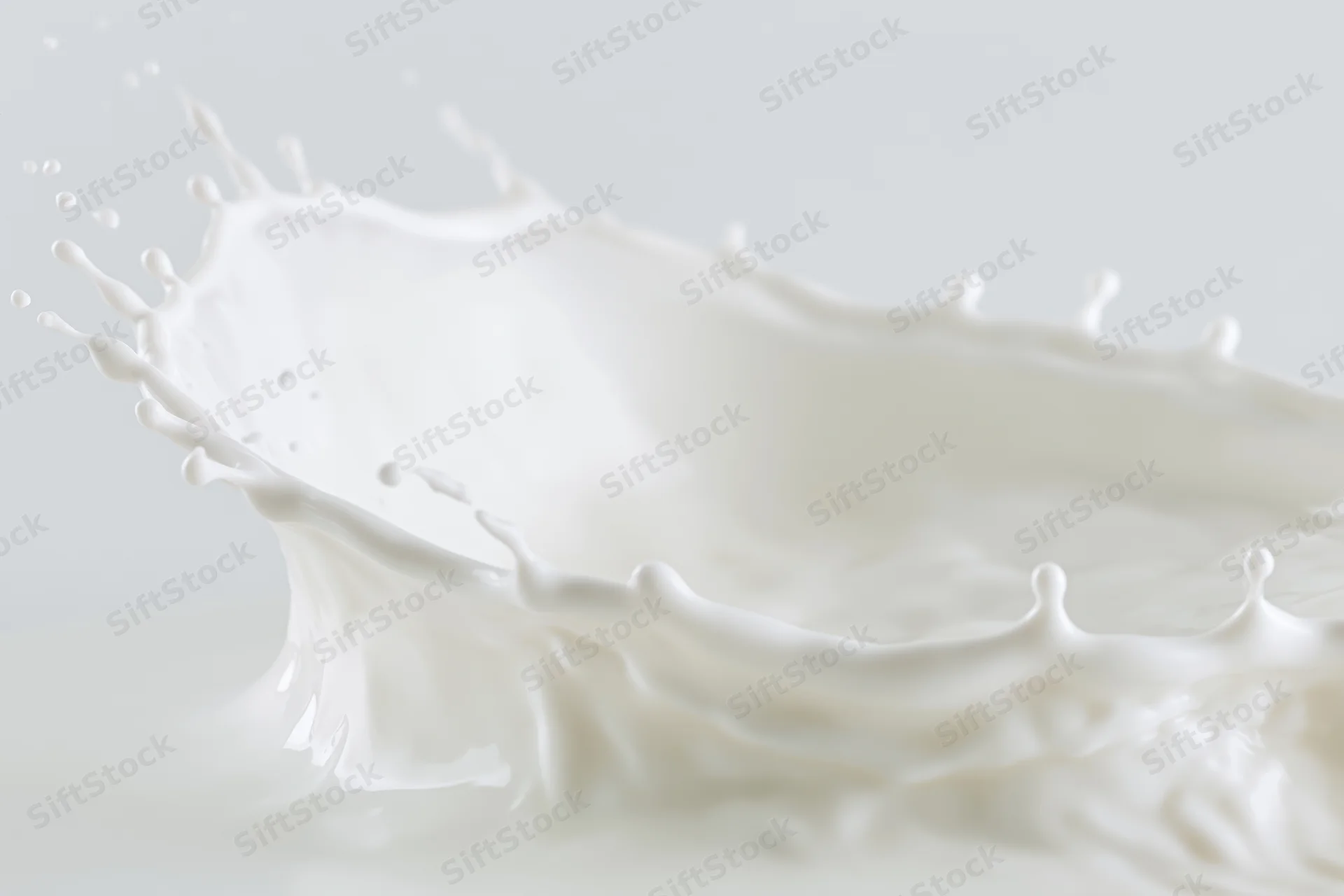 White milk mid-splash forming a crown-shaped wave in motion against a plain background