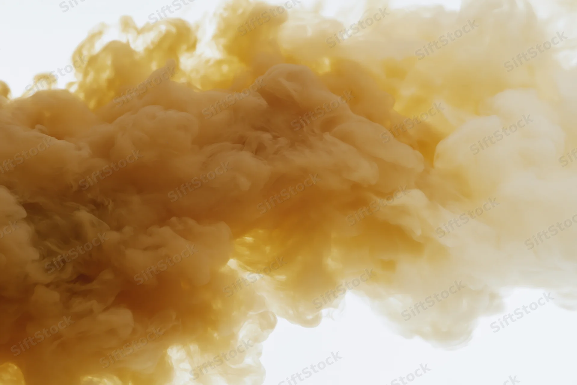 Golden amber ink dispersing in clear water forming swirling clouds against white background