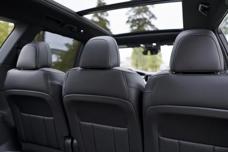 Three rear passenger seats in a mid-size suv interior with black leather upholstery and sunroof view