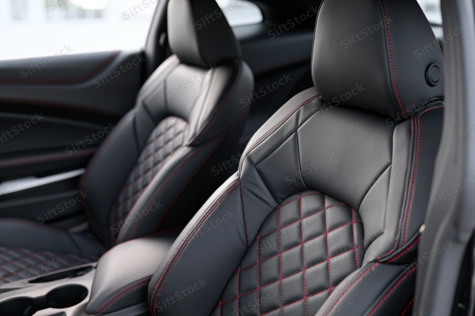 Black leather sport car seats with diamond stitching and red accents in vehicle interior