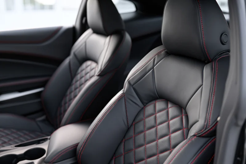 Black leather sport car seats with diamond stitching and red accents in vehicle interior