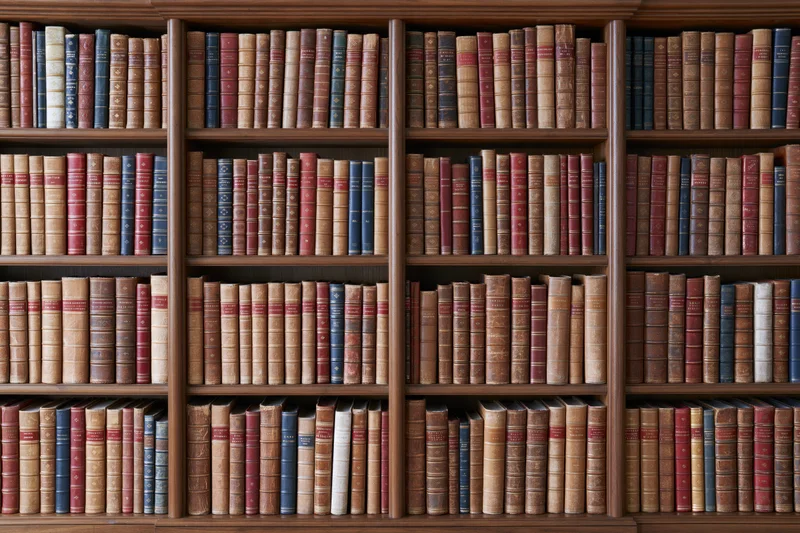Dark walnut bookcase filled with rows of vintage leatherbound books arranged on multiple shelves