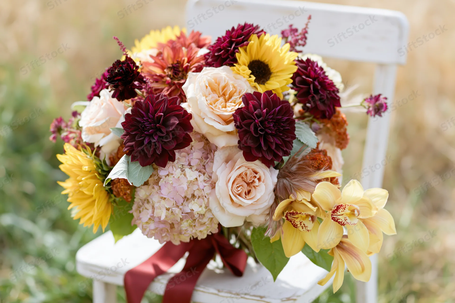 Lush autumn bridal bouquet resting on white wooden chair outdoors
