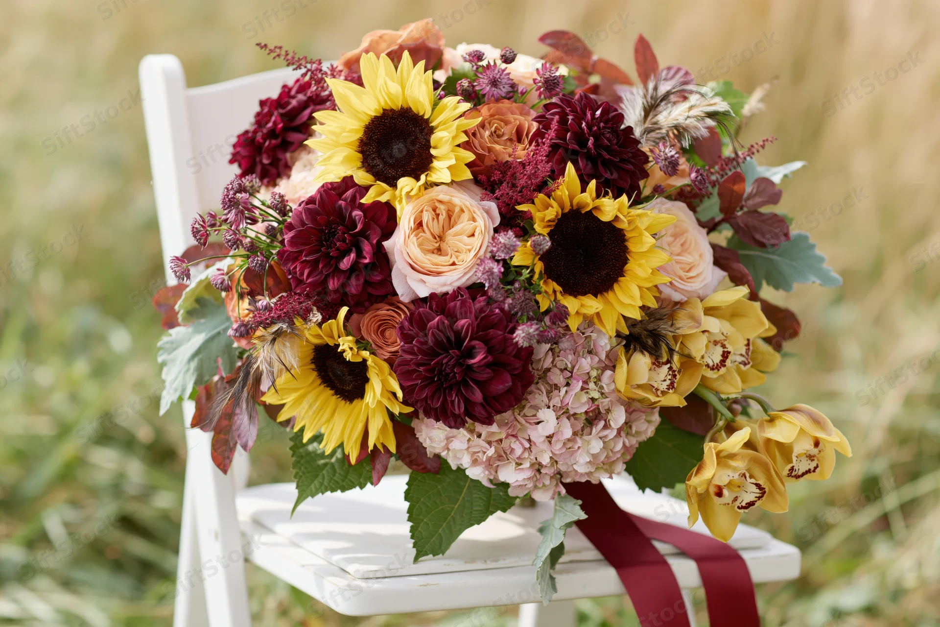 Lush autumn bridal bouquet resting on white wooden chair outdoors