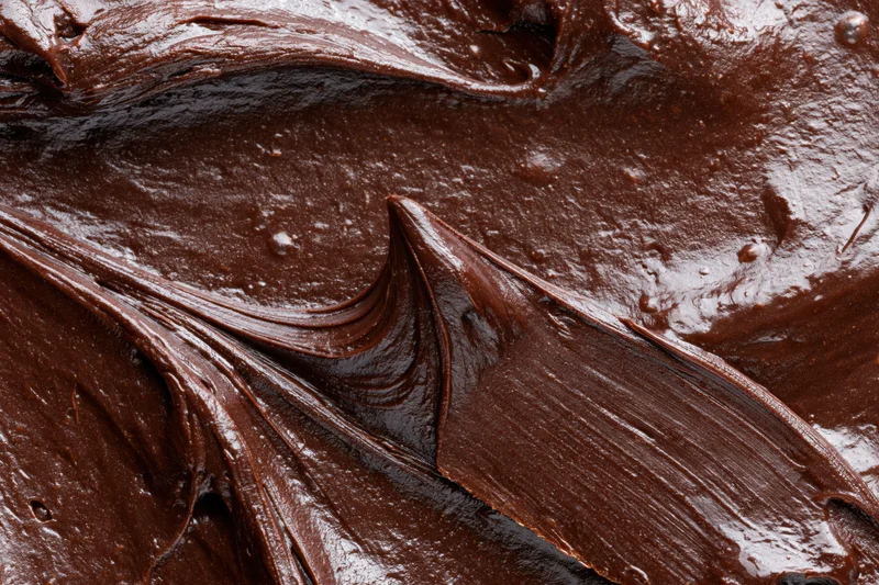 Thick melted dark chocolate spread across a flat surface in glossy swirls