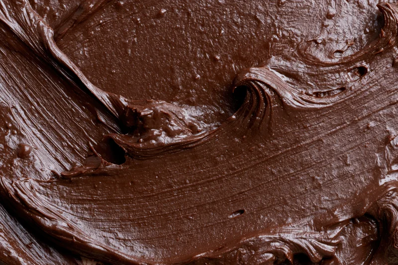 Thick melted dark chocolate spread in swirling patterns across a flat surface
