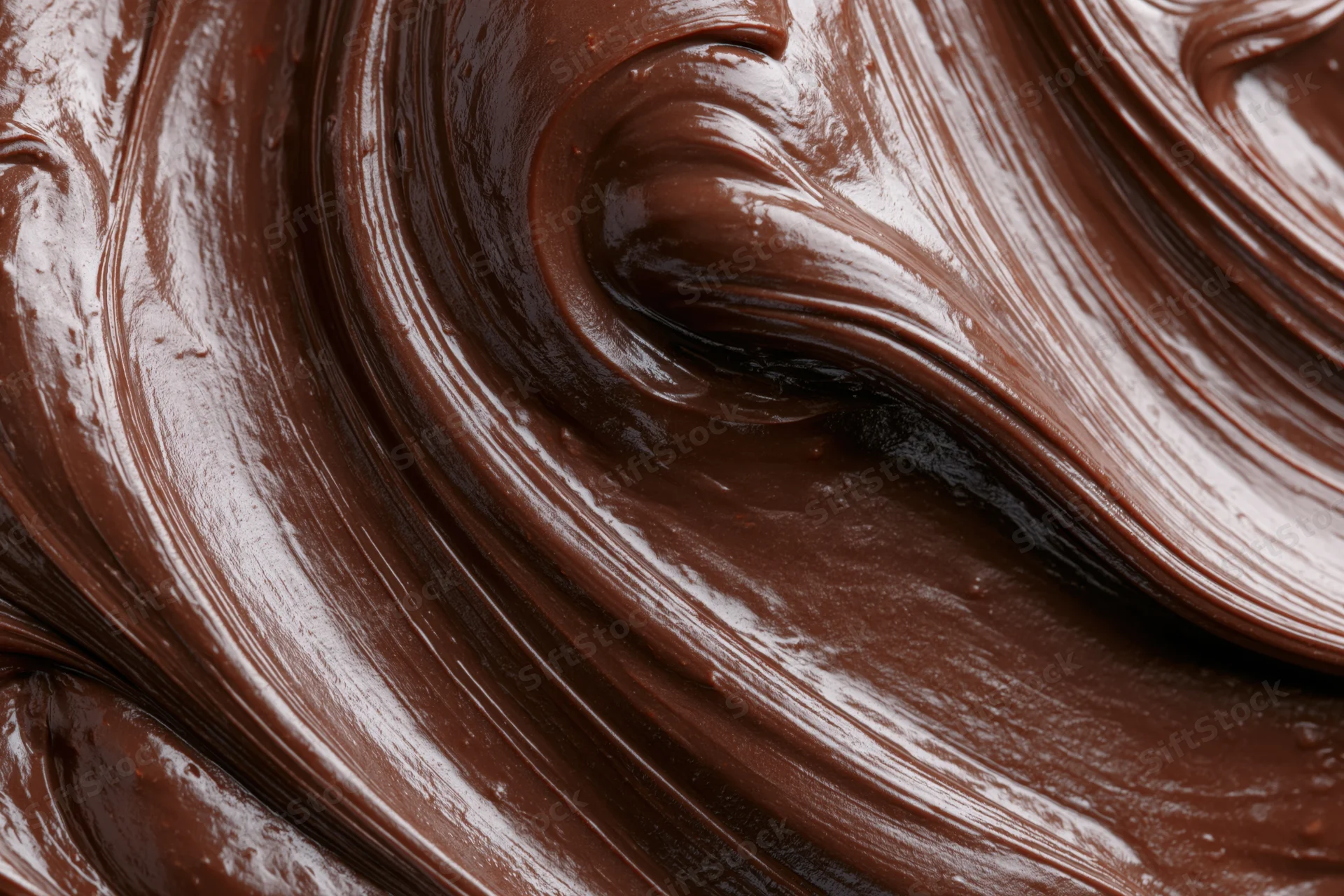 Melted dark chocolate swirled into flowing ridges and curves in closeup view