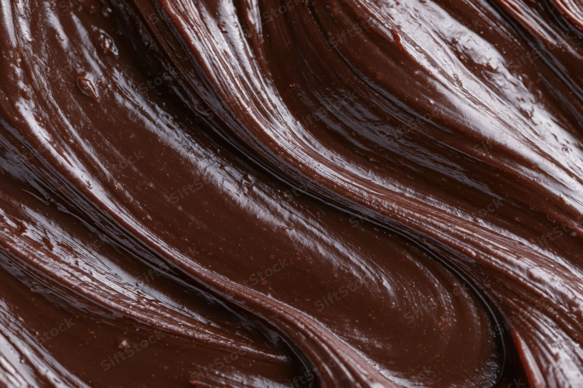 Melted dark chocolate swirled into flowing ridges and curves across a smooth surface