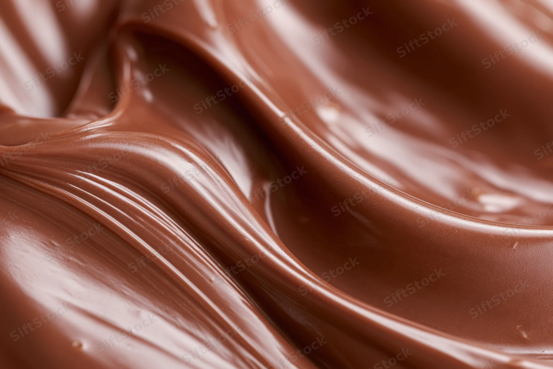 Melted milk chocolate flowing in smooth sweeping waves closeup