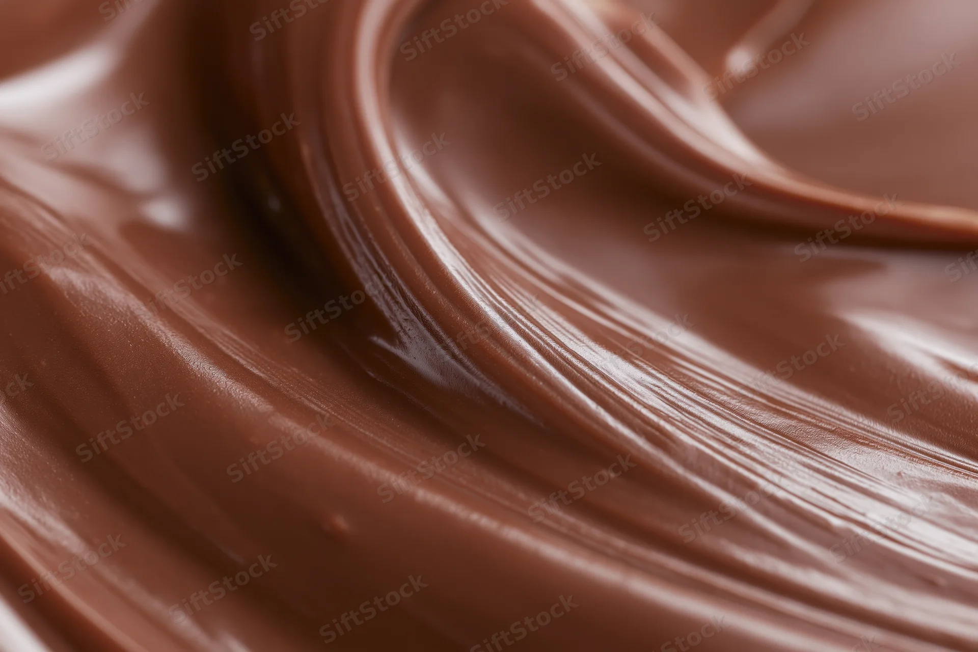 Melted milk chocolate flowing in smooth sweeping waves, close-up view of glossy texture