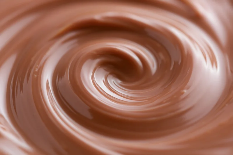 Molten milk chocolate swirling in a tight spiral closeup