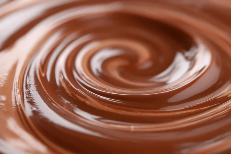 Molten milk chocolate swirling in a tight spiral in extreme closeup