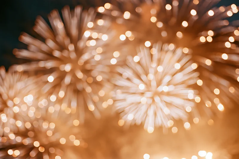 Fireworks bursting across night sky in warm golden bokeh display