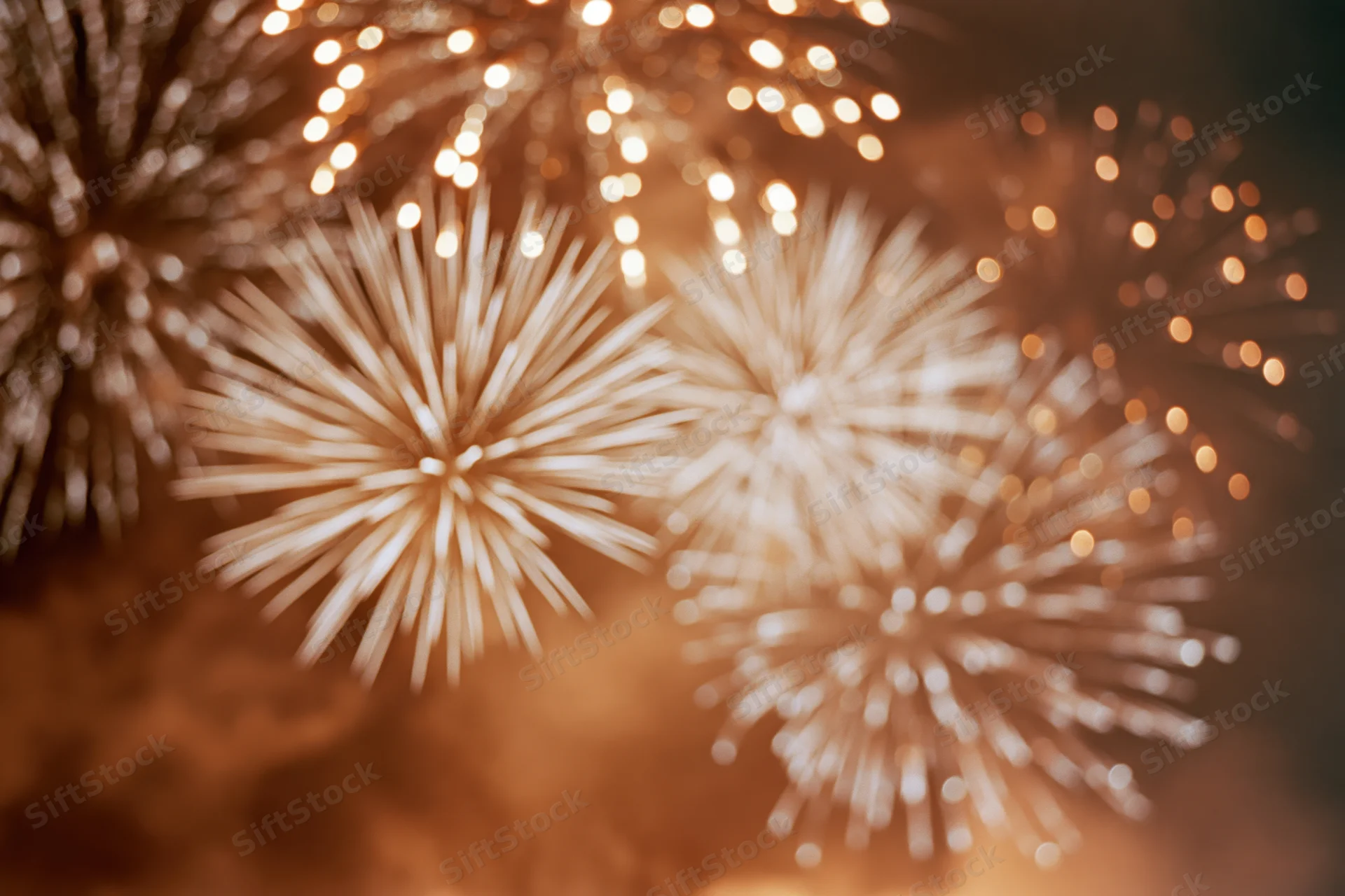 Fireworks bursting across night sky in warm golden light with bokeh effect