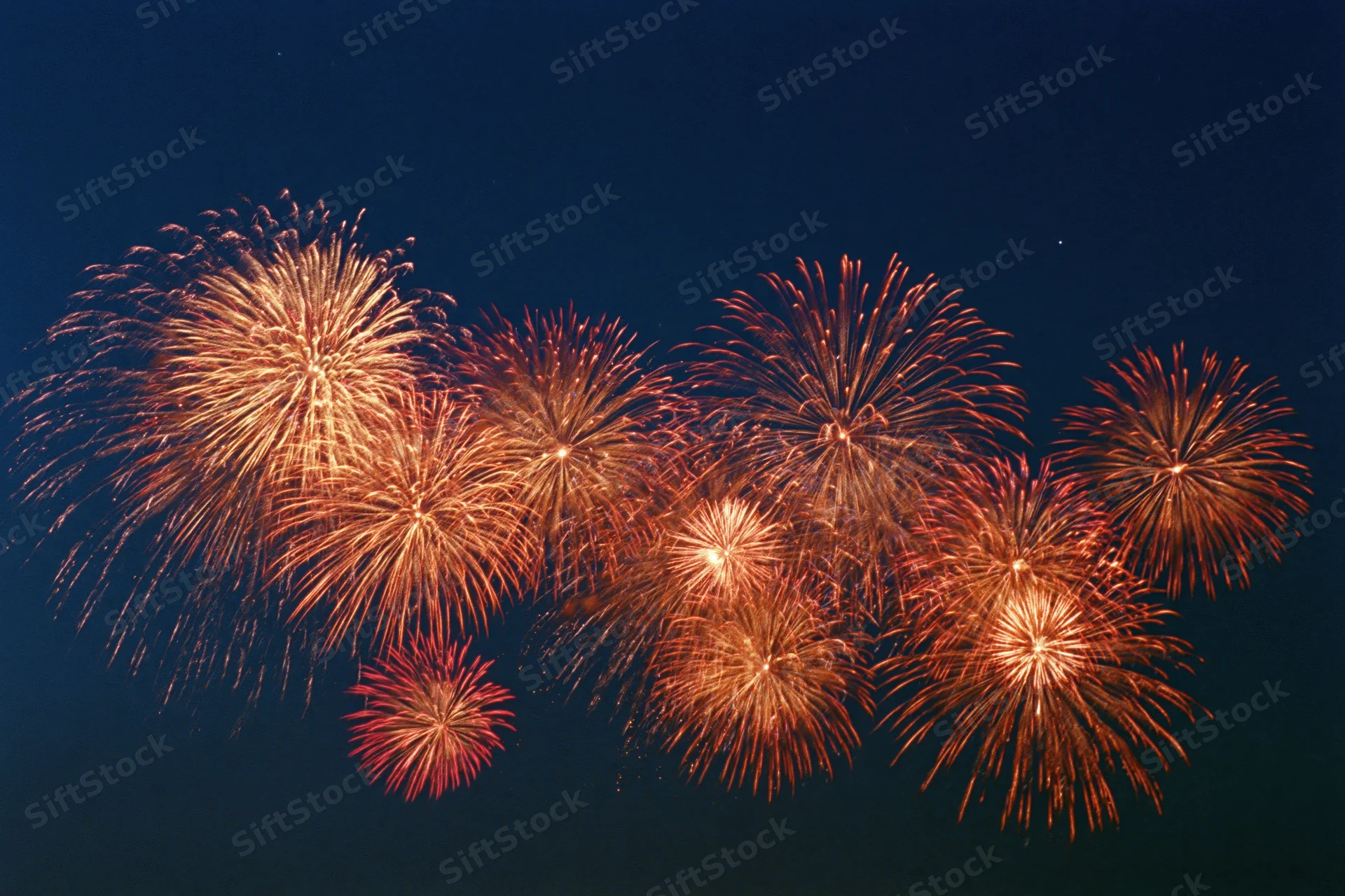 Multiple fireworks bursting simultaneously across the night sky