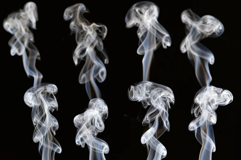 White smoke wisps arranged in a grid pattern against a black background