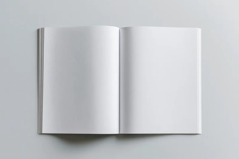 Open blank softcover book lying flat with both pages visible on a neutral gray surface