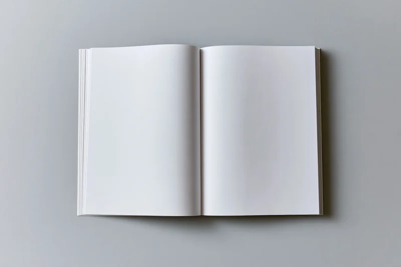 Open blank softcover book lying flat with both pages visible on a plain surface