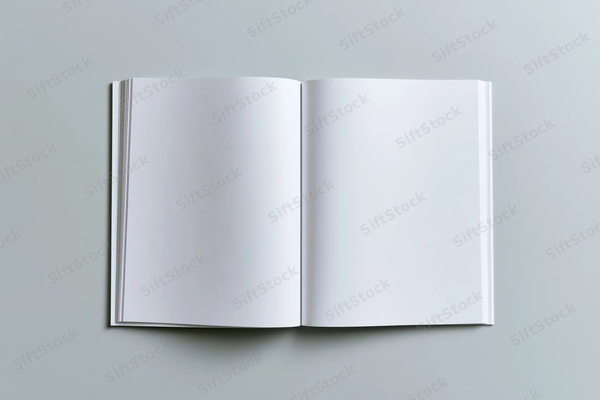 Open blank softcover book lying flat with both pages visible on a gray surface