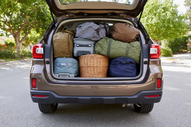 Open trunk of dark bronze suv packed with luggage and bags on residential street