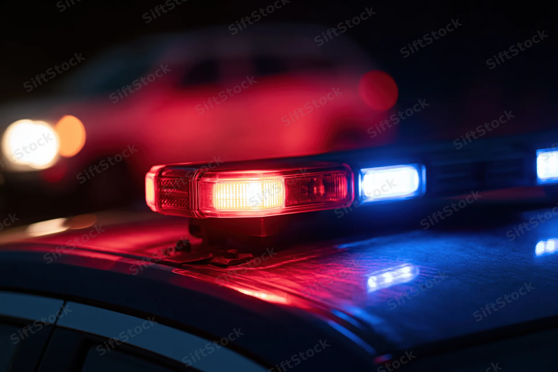 Police car light bar flashing red and blue at night close-up on rooftop
