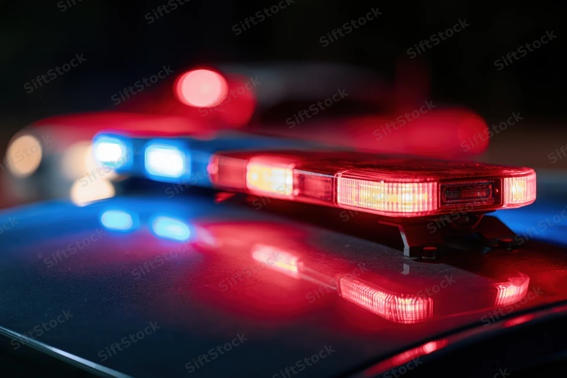 Police car light bar flashing red and blue at night close-up on rooftop