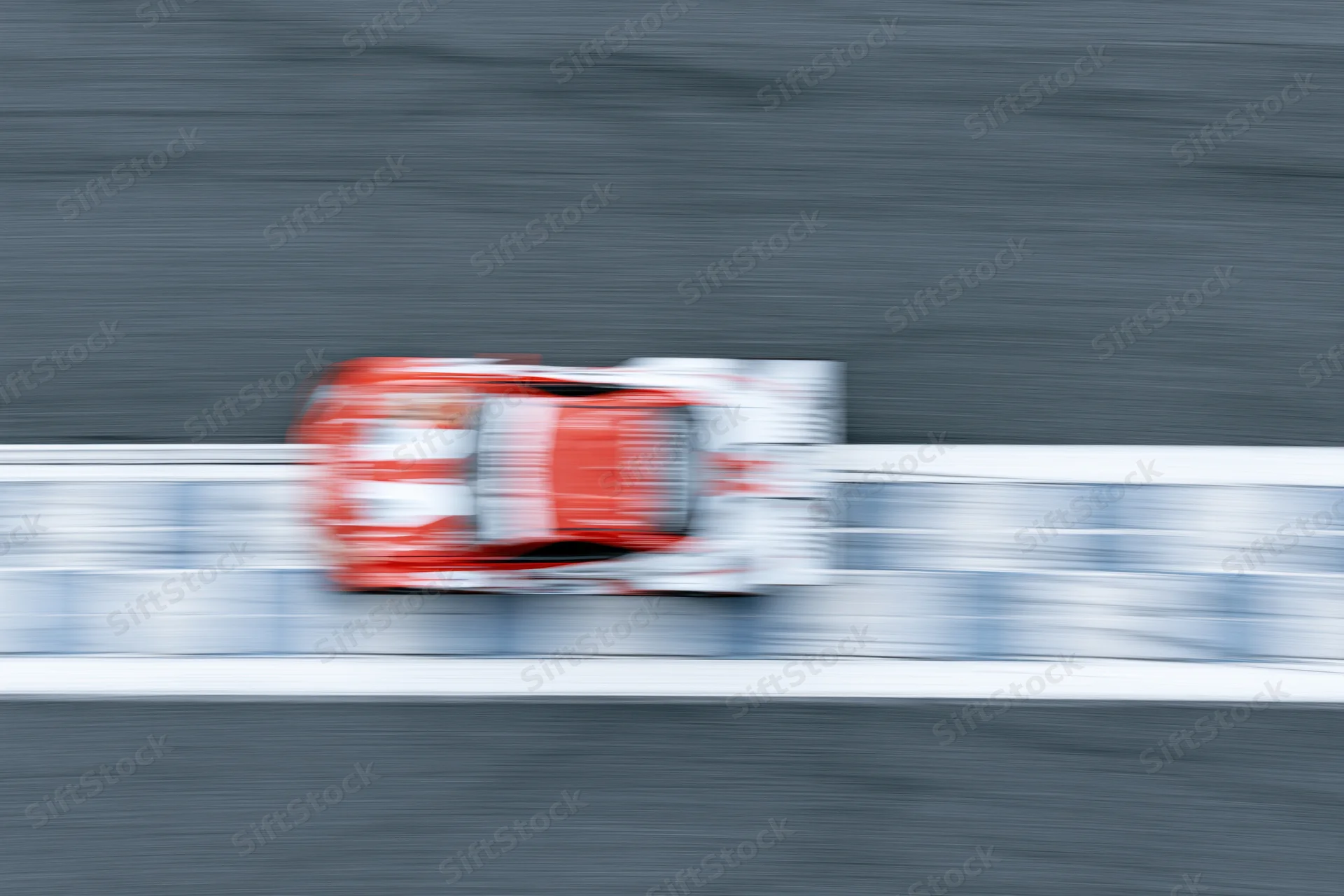 Red and white gt racing car crossing painted finish line on racetrack at high speed