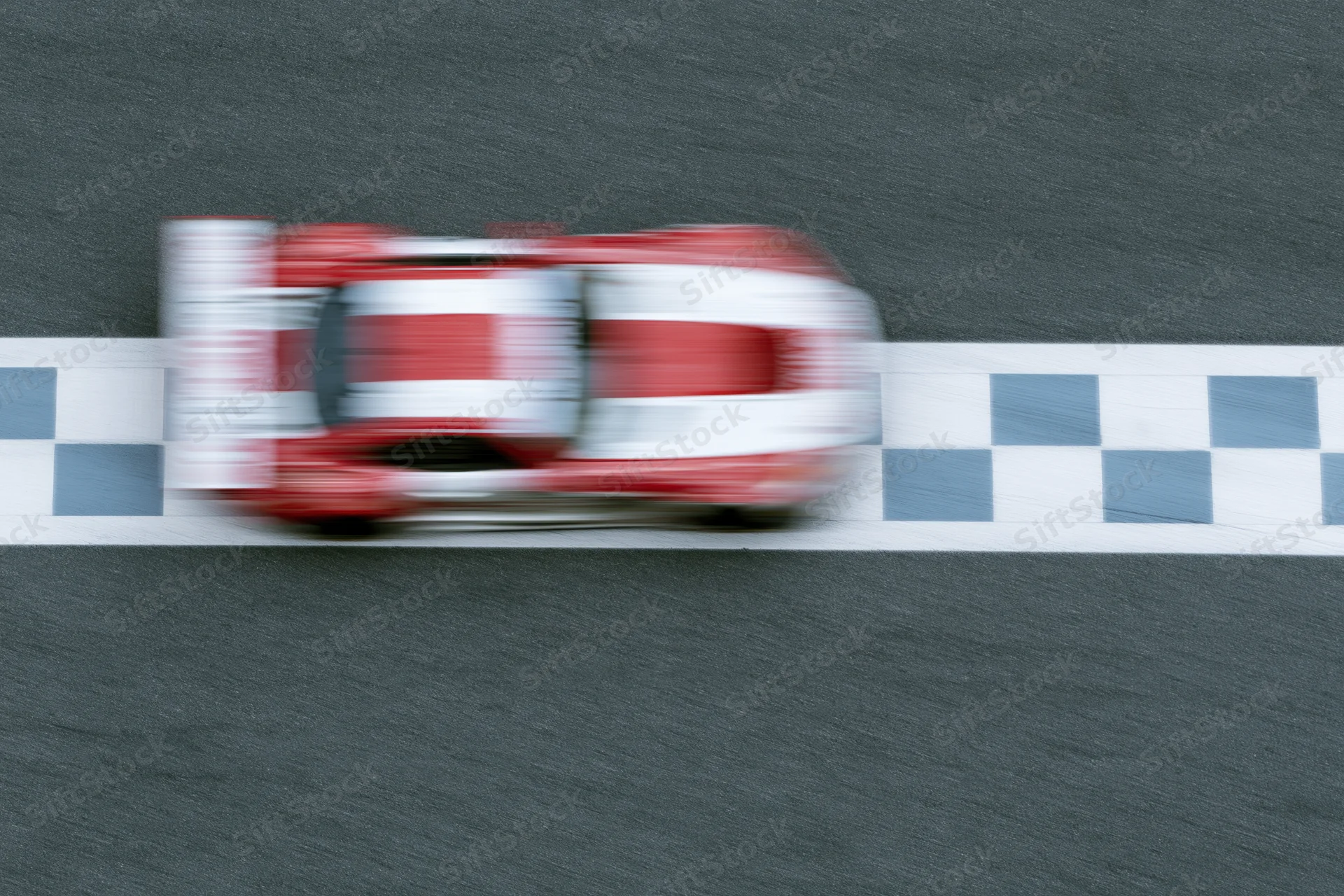 Red and white gt racing car crossing checkered finish line on asphalt track with motion blur