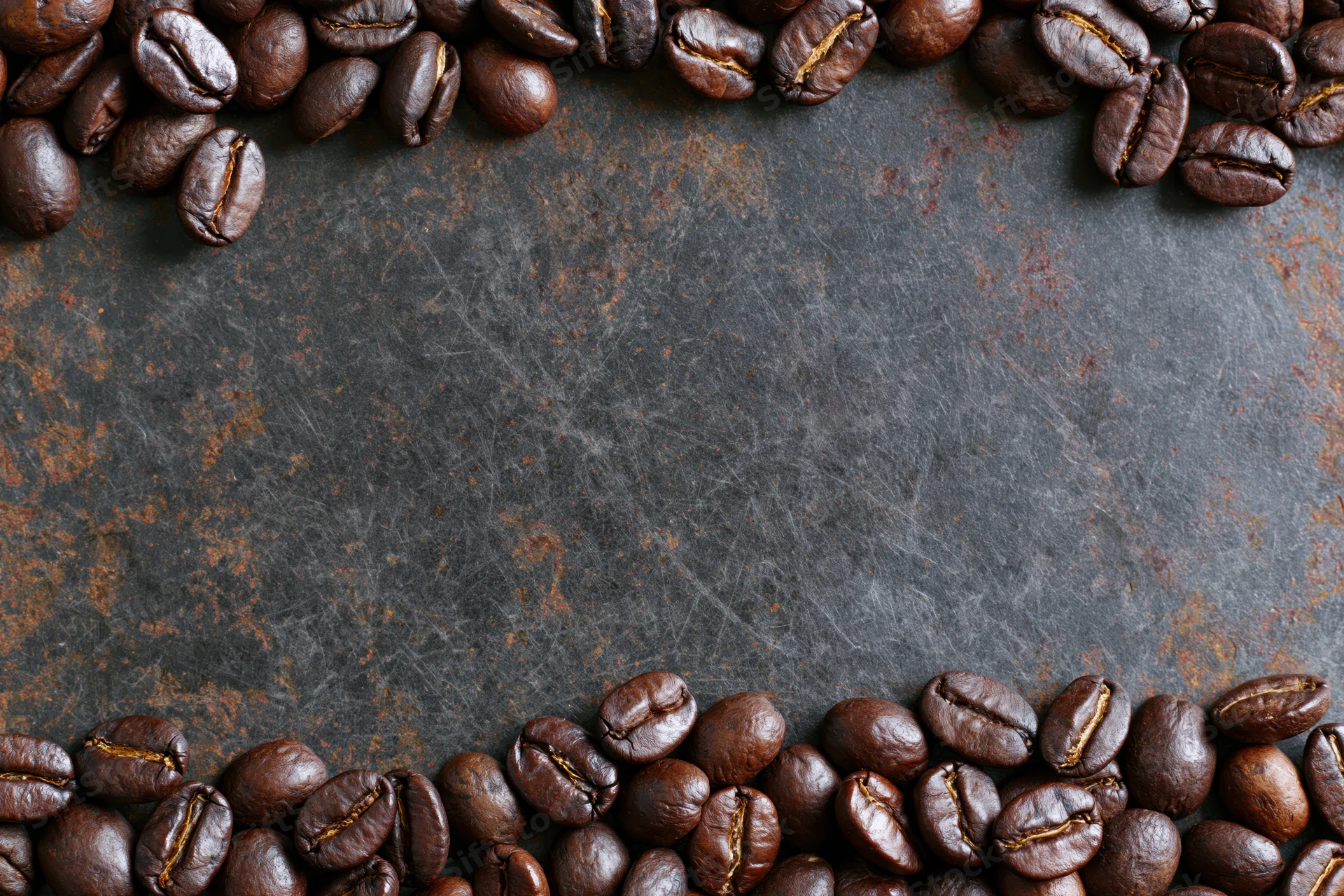 Roasted coffee beans arranged along top and bottom edges on dark textured surface