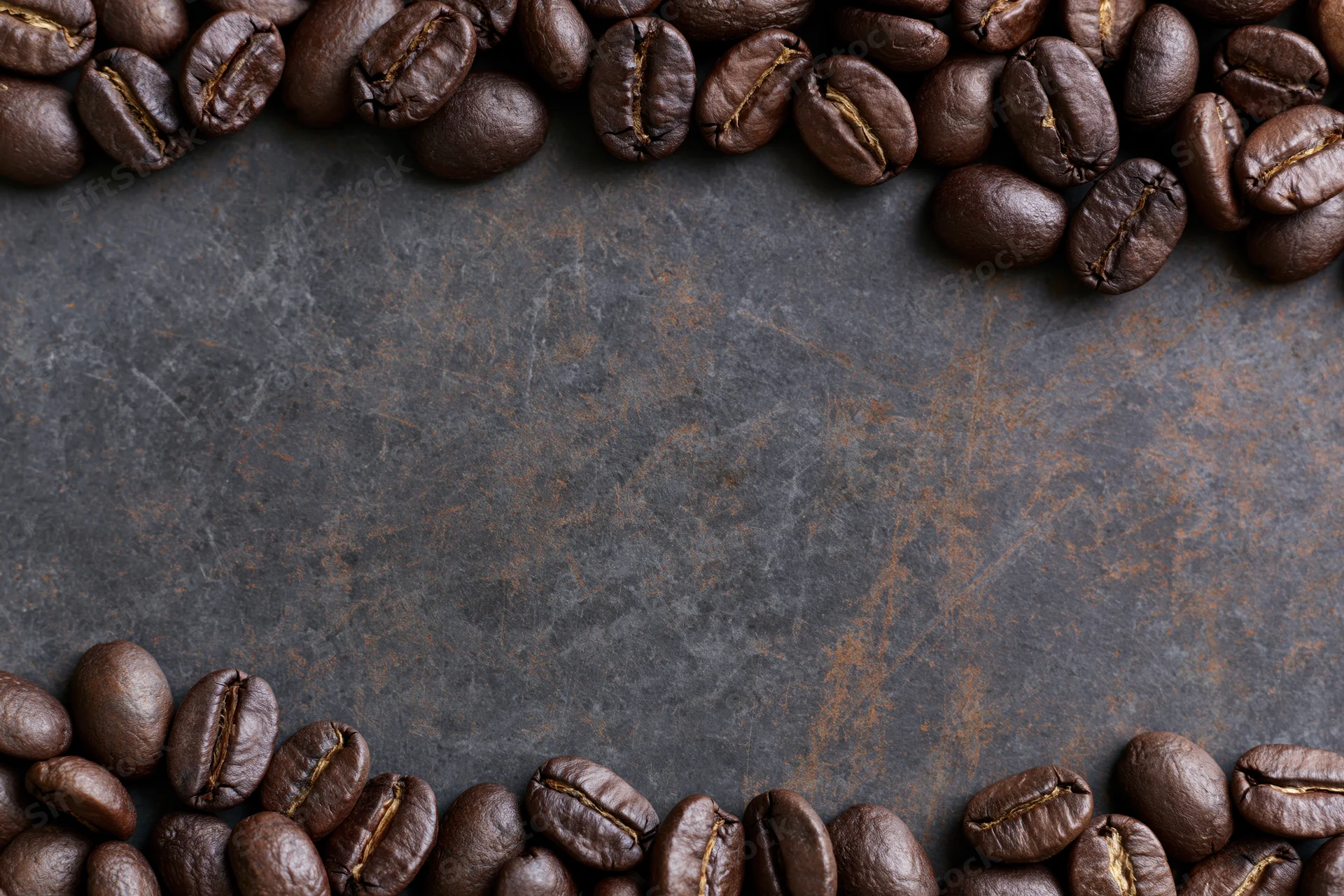 Roasted coffee beans arranged along top and bottom edges on dark stone surface