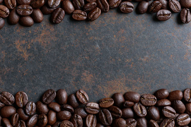 Roasted coffee beans arranged along top and bottom edges on dark textured surface