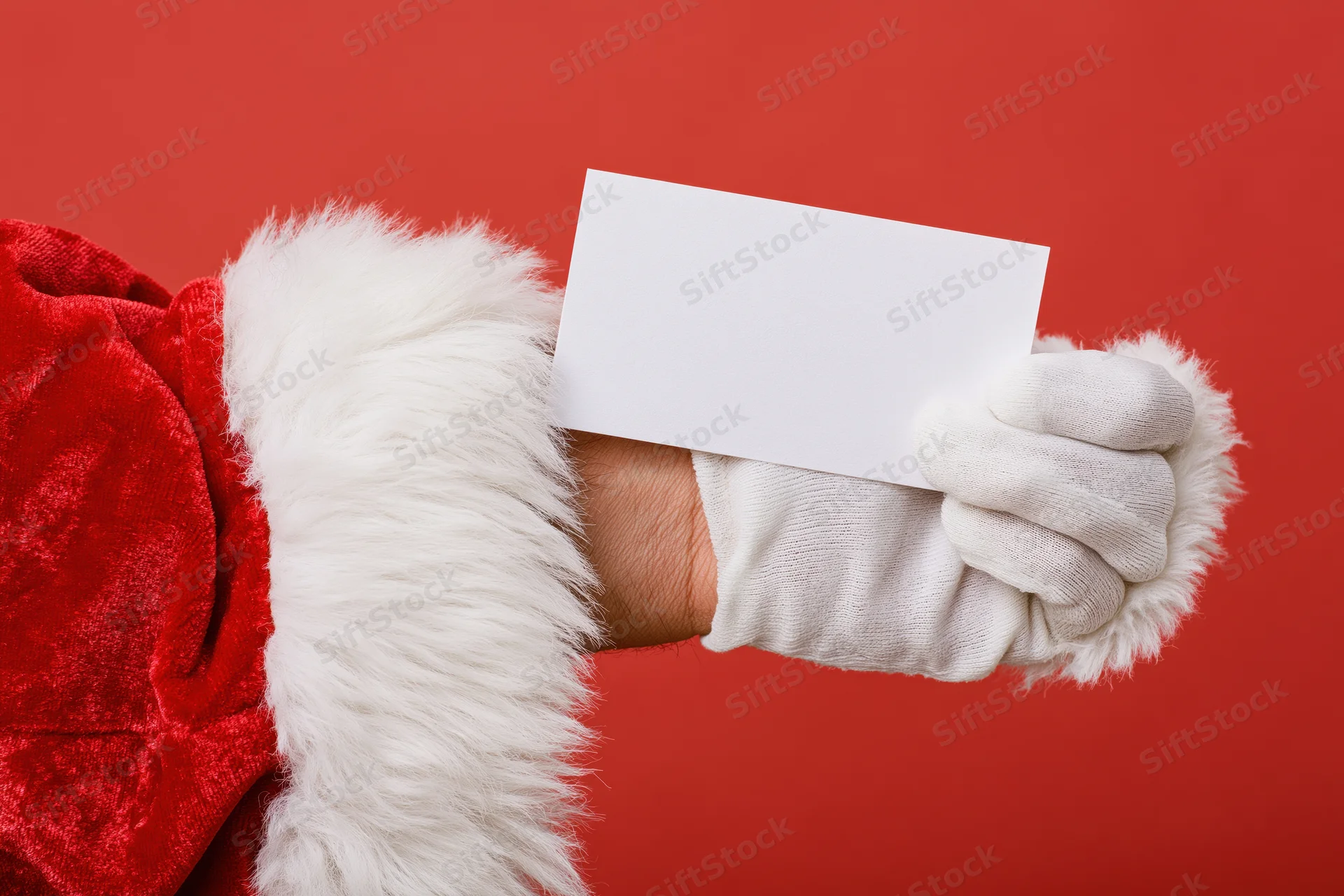 Santa claus hand in white glove holding blank white card against red background