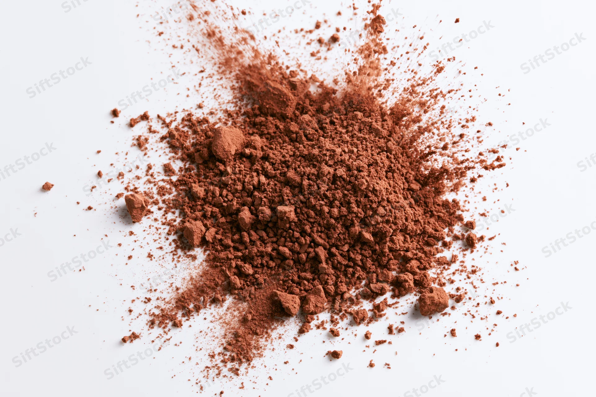 Scattered cocoa powder and coarse brown spice granules on white surface