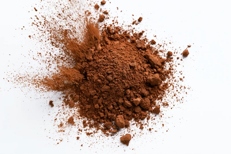 Scattered cocoa powder and coarse brown spice granules on white surface