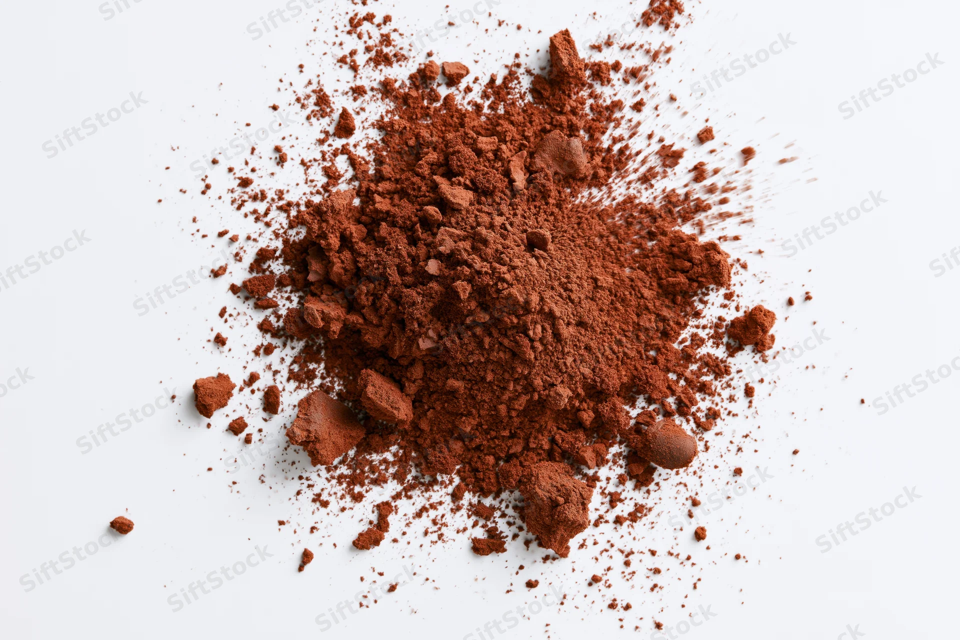 Scattered cocoa powder and brown spice granules on white background