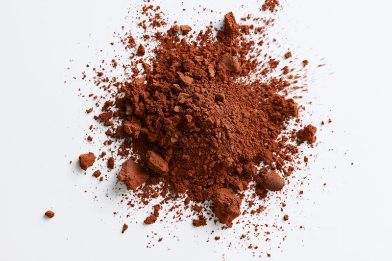Scattered cocoa powder and brown spice granules on white background