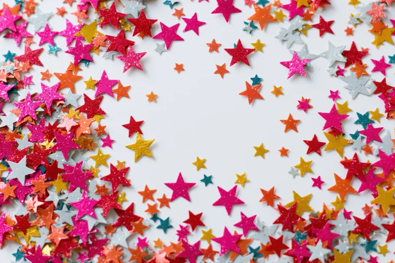 Star-shaped confetti scattered across white surface with copyspace in center