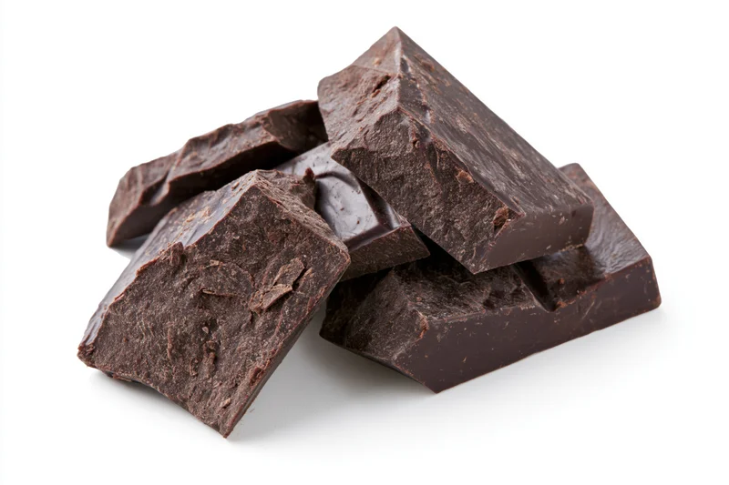 Broken dark chocolate chunks stacked on white background