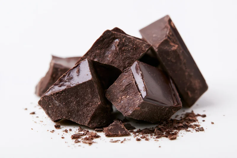 Broken dark chocolate chunks scattered on a white background