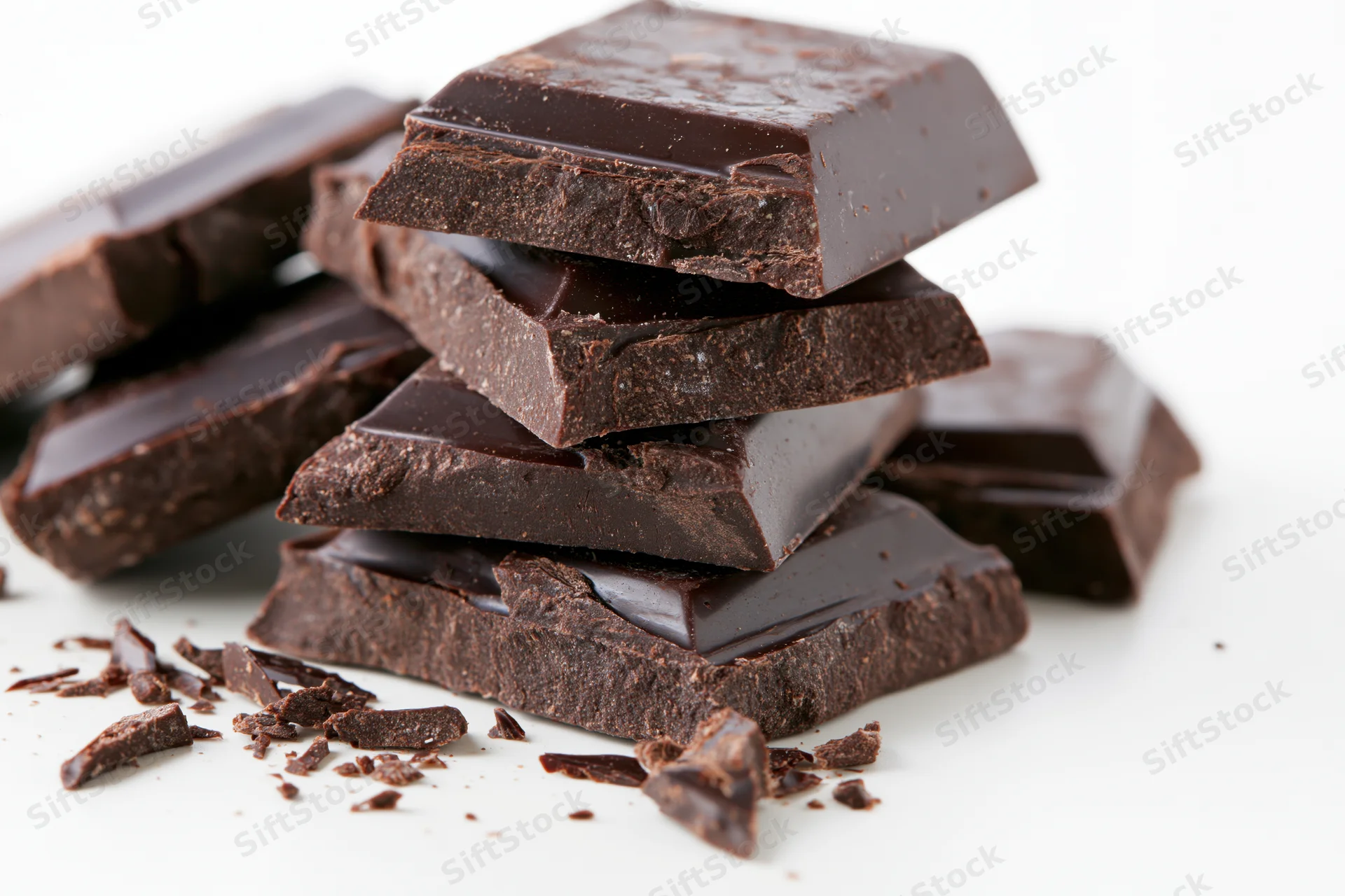 Broken dark chocolate pieces stacked loosely on a white background