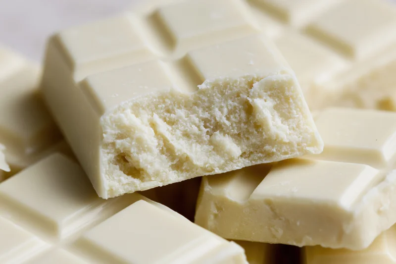 Broken white chocolate squares piled together in closeup view