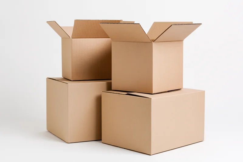 Several cardboard moving boxes stacked and arranged in a loose formation on a white surface