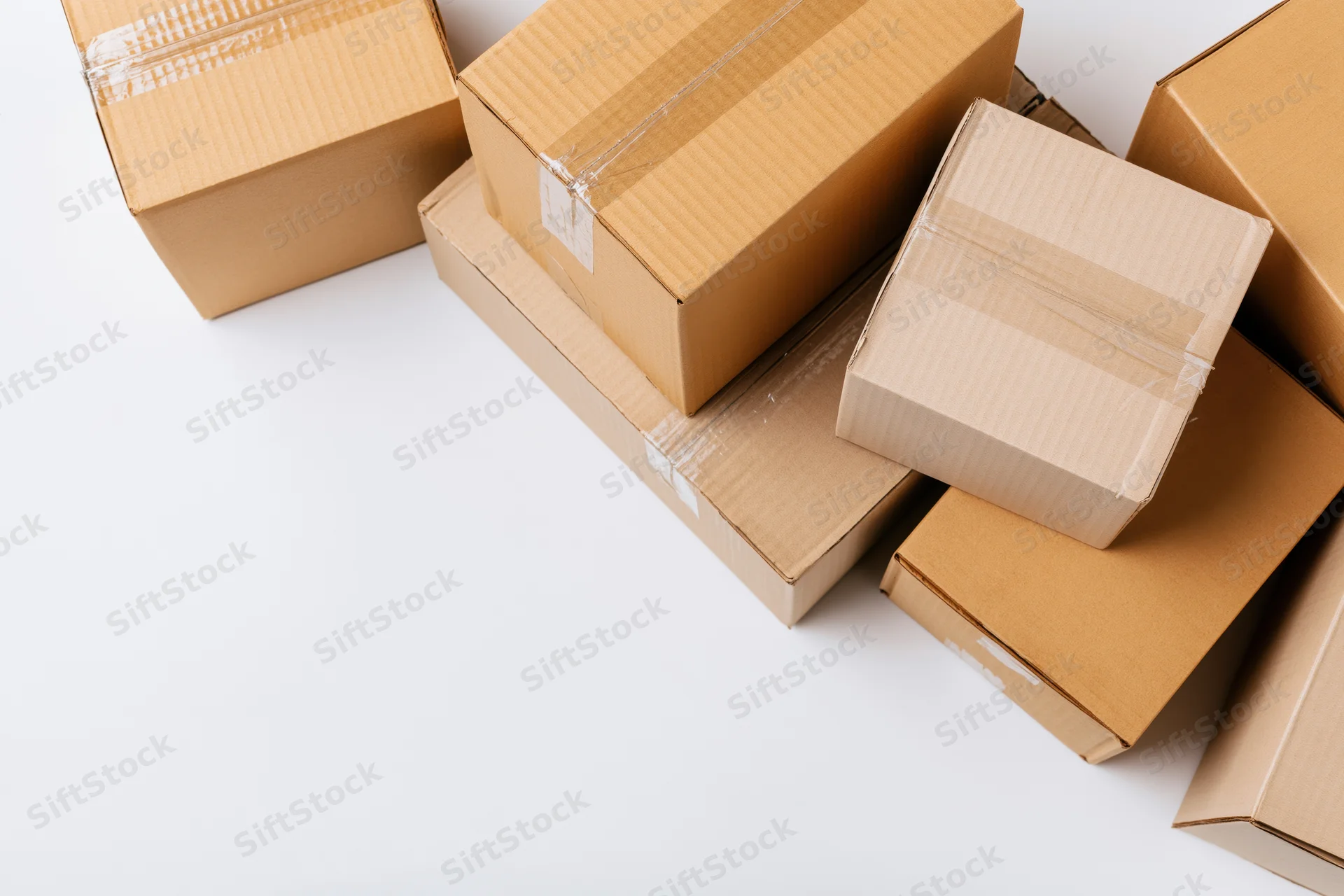 Closed cardboard shipping boxes of various sizes stacked on white surface