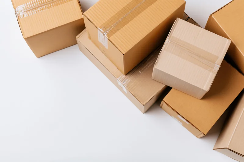Closed cardboard shipping boxes of various sizes stacked on white surface