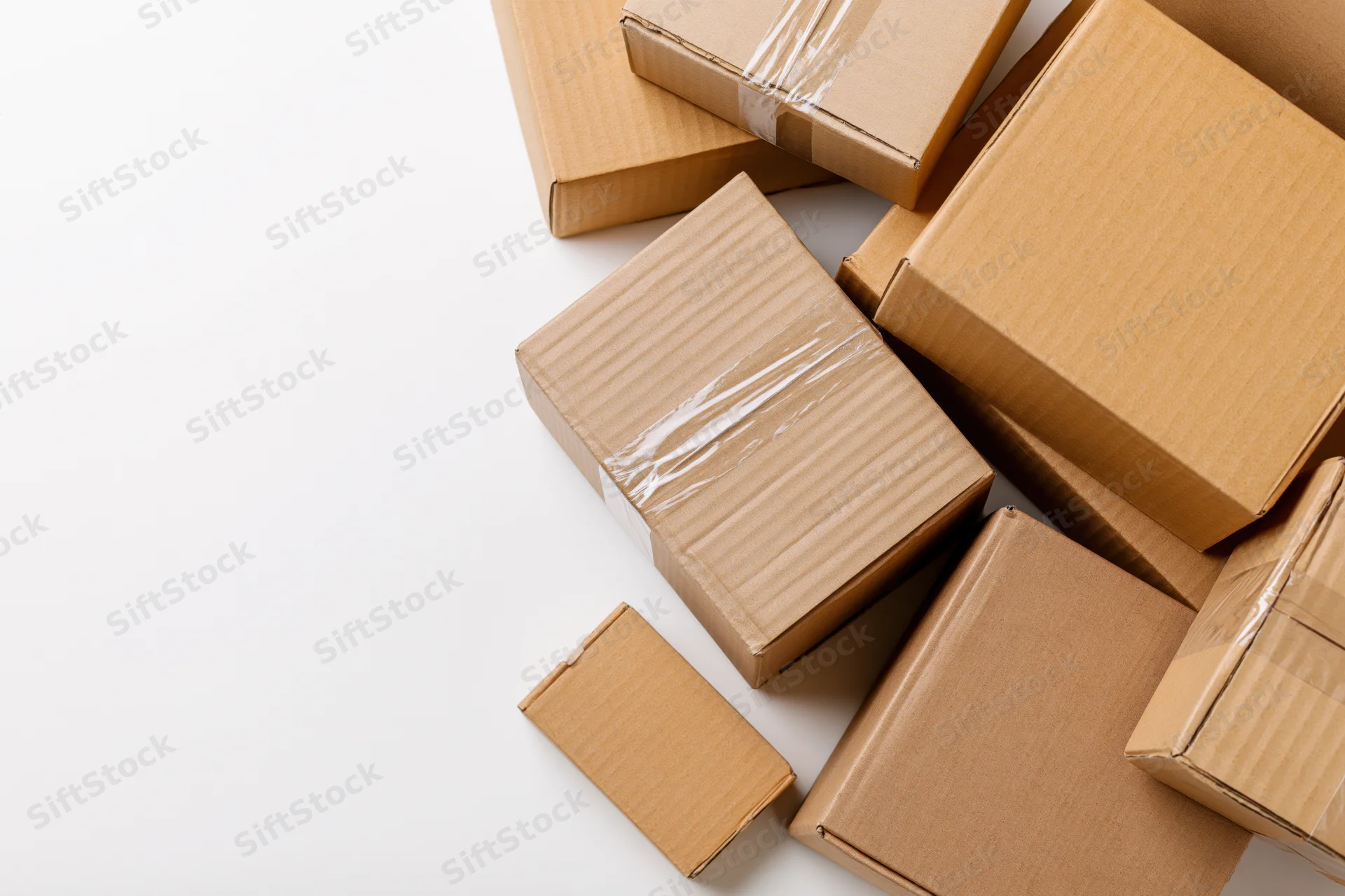 Closed cardboard shipping boxes of various sizes arranged in a cluster on a white background with copyspace