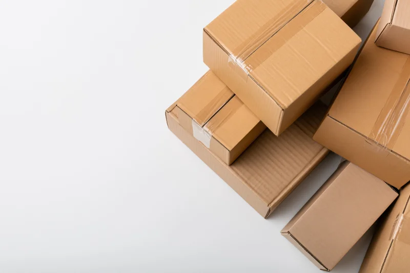 Closed cardboard shipping boxes stacked on white surface with copyspace