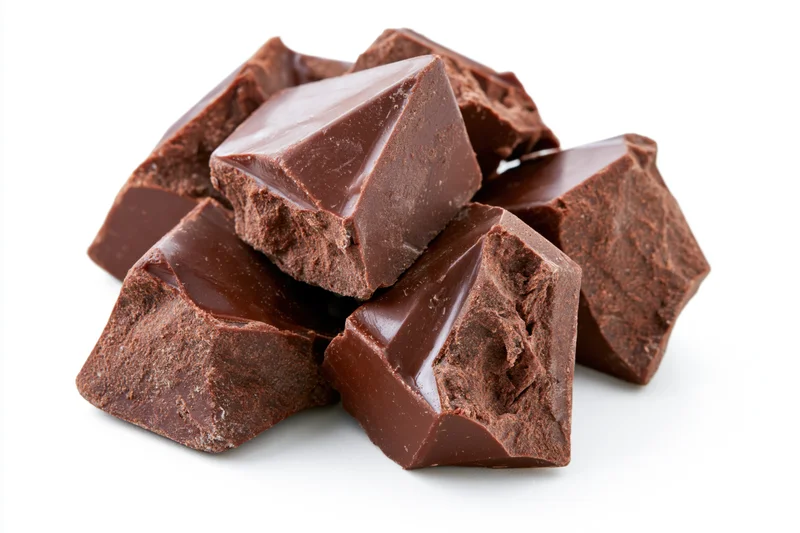 Rough-broken chunks of dark milk chocolate piled loosely on white background